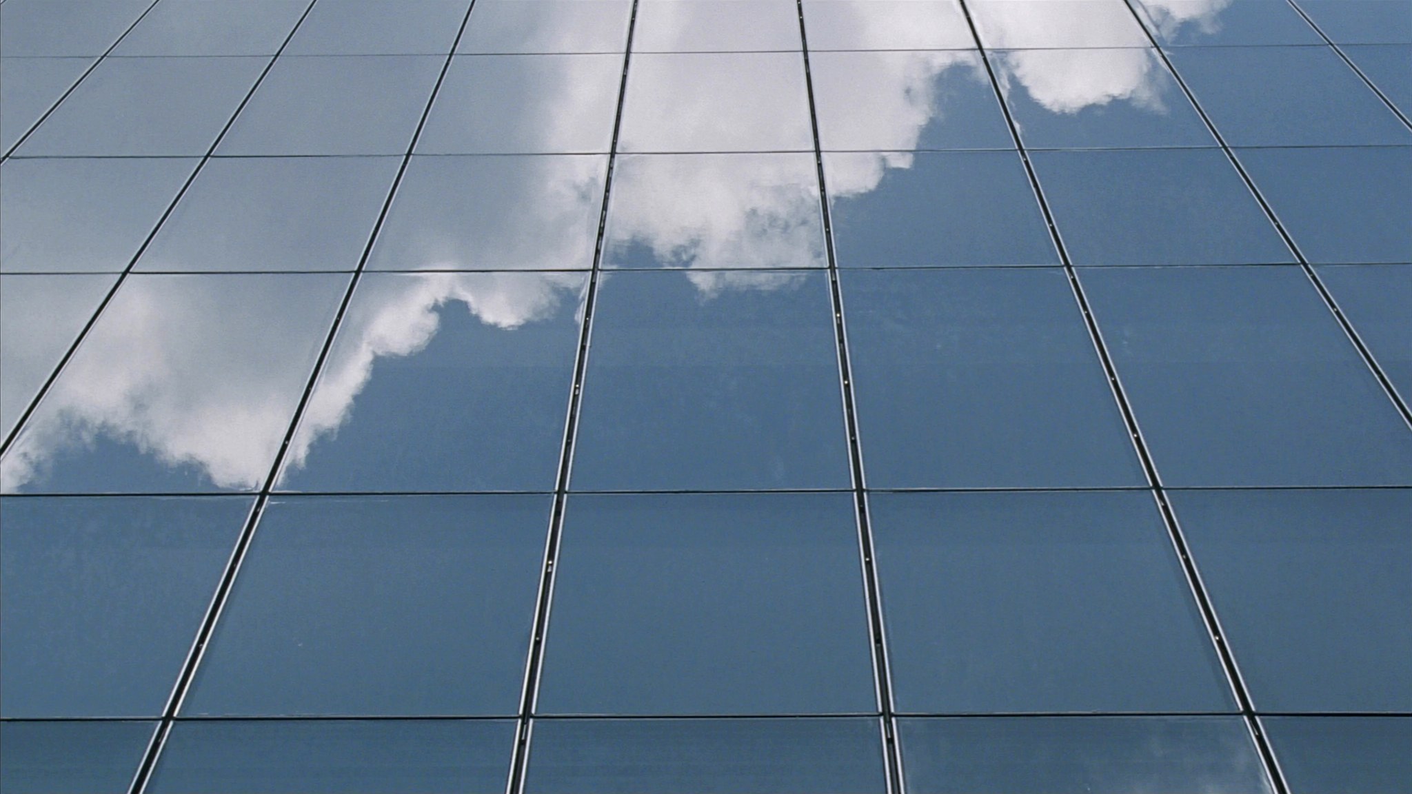 A glass tower façade rises above a landscaped office entrance.