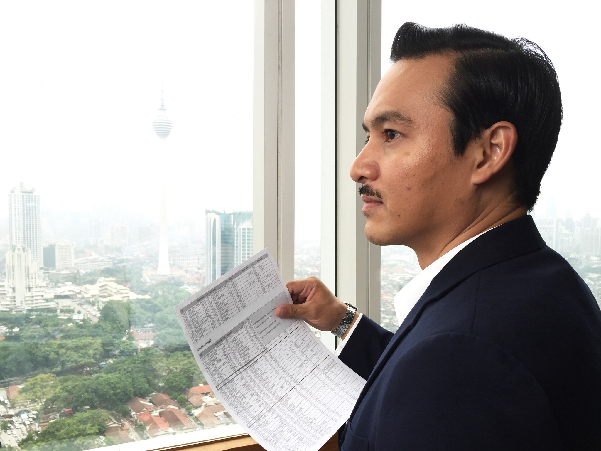 Property owner reading a quotation beside a Kuala Lumpur view.
