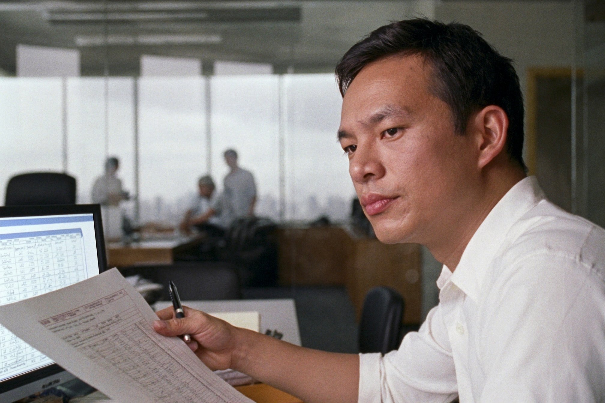 Office colleague reviewing a report beside a laptop.